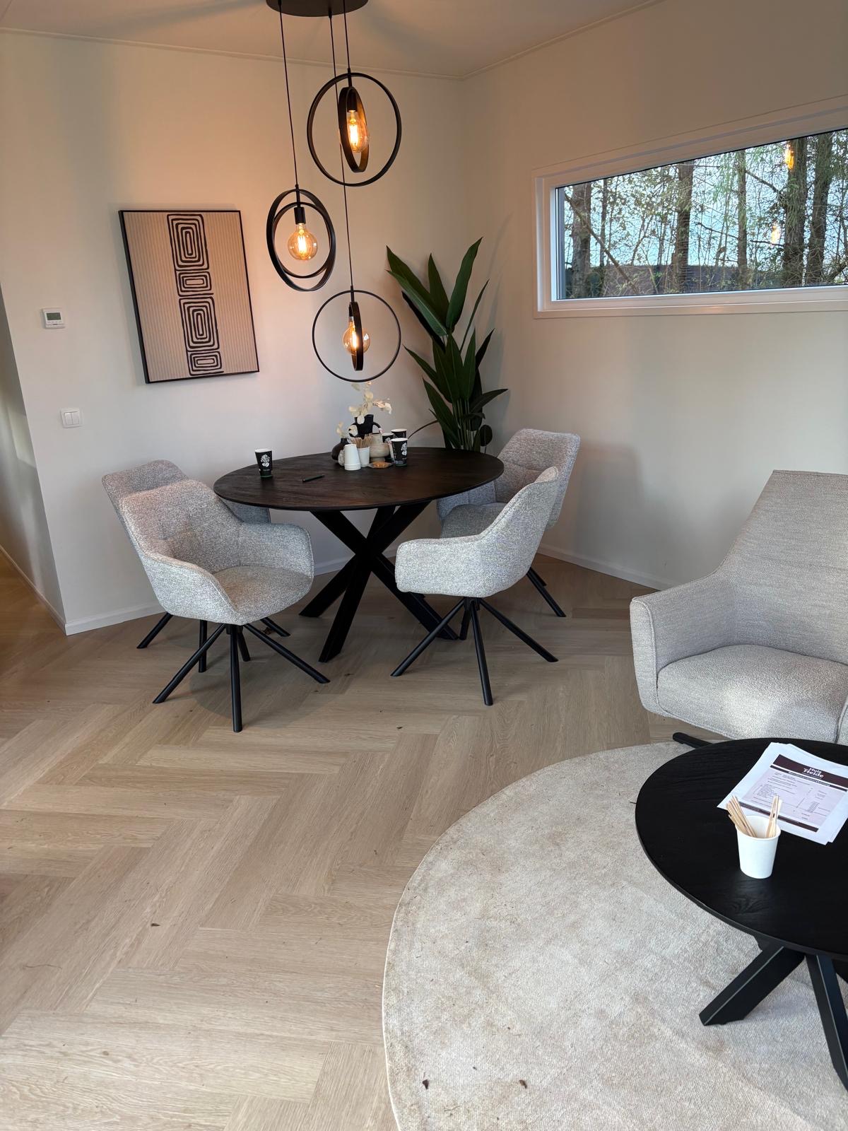 Woonkamer en eethoek in de modelwoning met visgraatvloer, ronde eettafel en designverlichting