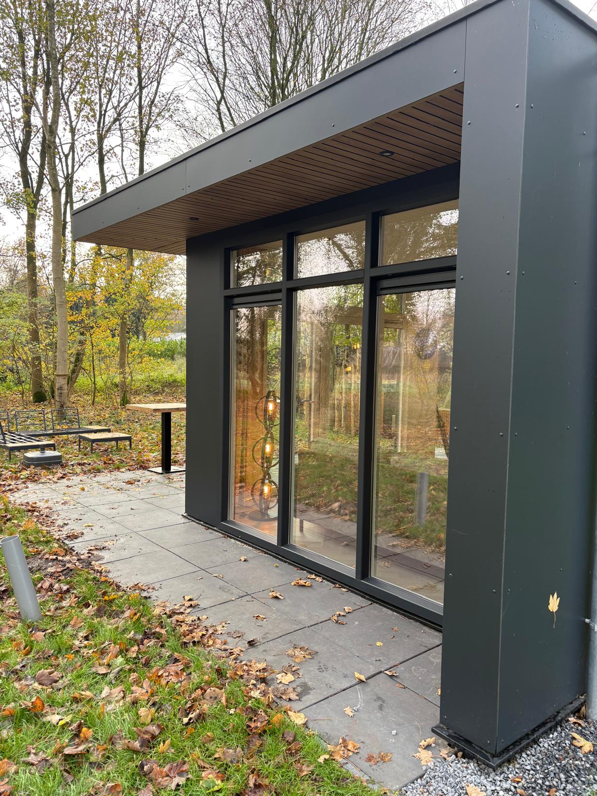 De modelwoning: strakke lodge met antraciet gevel, houten plafond en terras in herfstblad